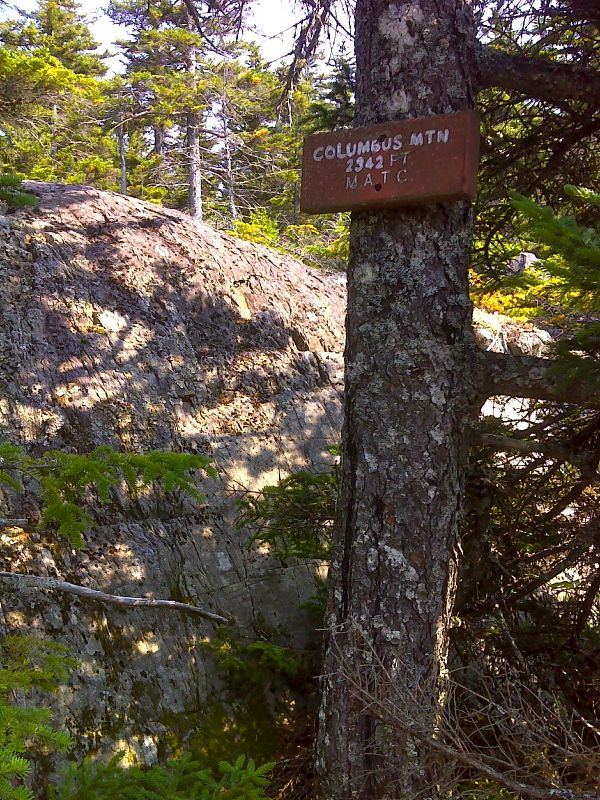 mm 4.9 Inconspicuous sign for Columbus Mountain. It is not  actually at the summit.  GPS N45.4496 W 69.2706  Courtesy pjwetzel@gmail.com