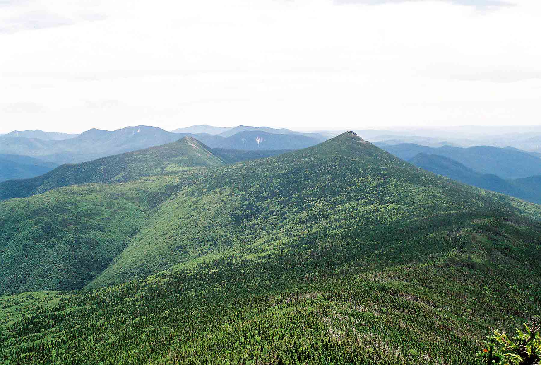 mm 23.0 - South from Little Haystack. The southbound AT drops below tree line and follows the ridge to just north of Mt. Liberty (closer of the two conical mountains) then descends into Franconia notch on the right. The other conical mountain is Mt. Flume.  Courtesy dlcul@conncoll.edu