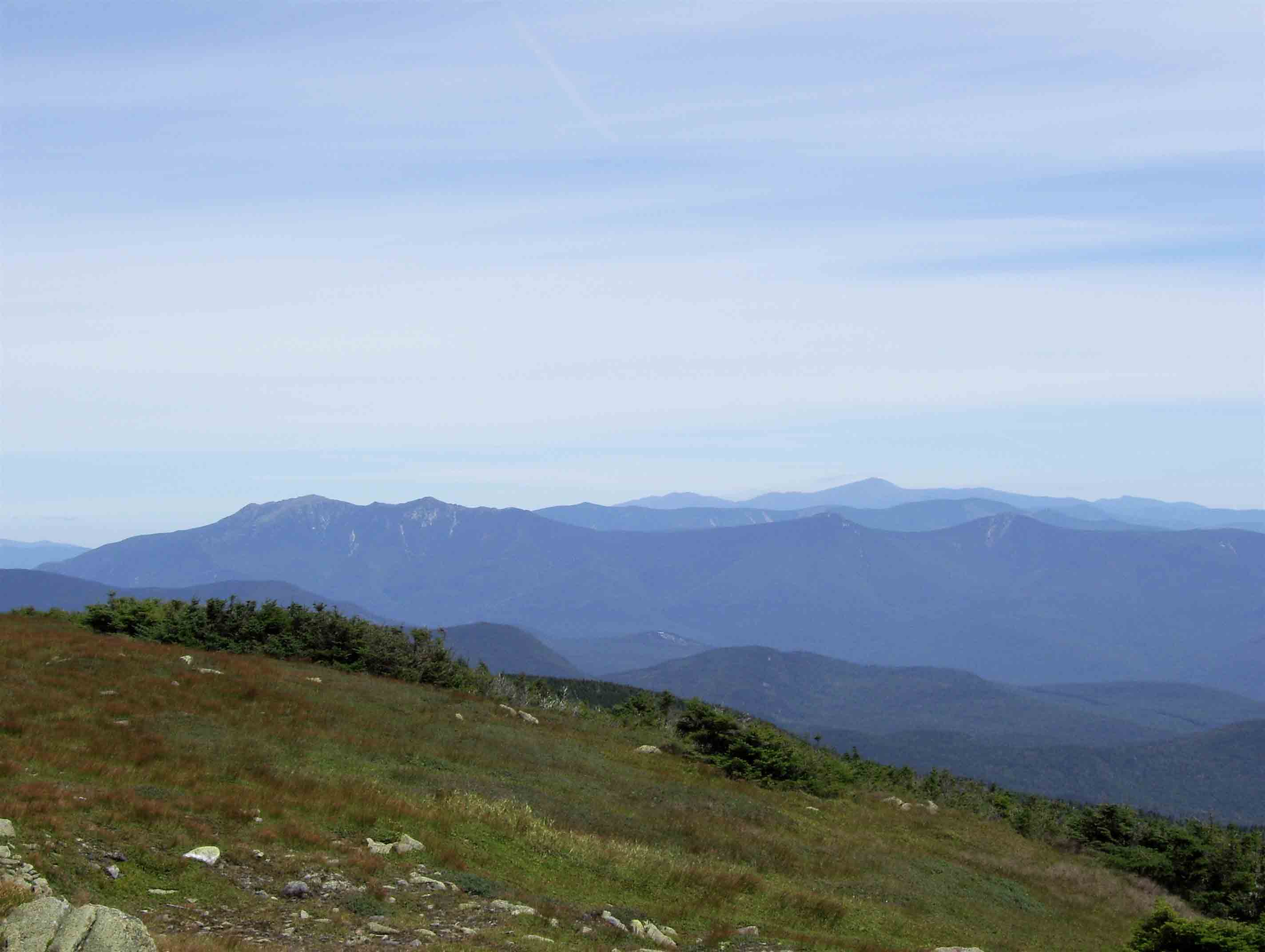 View of most of the central part of the White Mts. as seen from near the summit of Mt. Moosilauke. A plume of dark smoke can be seen just to the left of Mt. Washington, the highest peark in the far distance. This is from the Cog Railway.  Courtesy dlcul@conncoll.edu