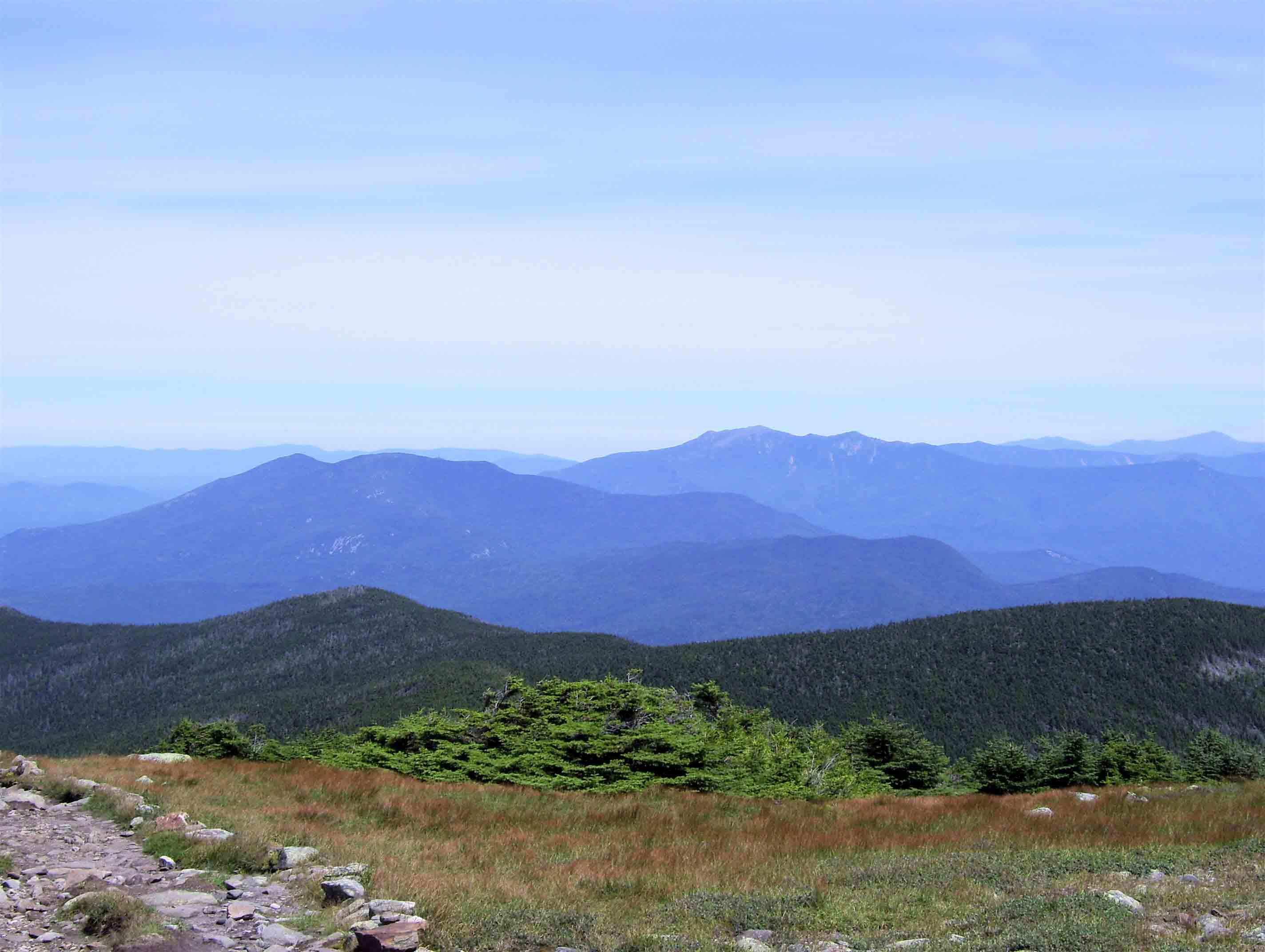 mm 3.8 - View to the northeast from near the summit of Mt. Moosilauke, showing the Kinsmans, the Franconia Range and in the far distance, the Presidential Range. The highest mountain seen is Mt. Washington on the far right side of the picture which is 60 trail miles away.  Courtesy dlcul@conncoll.edu