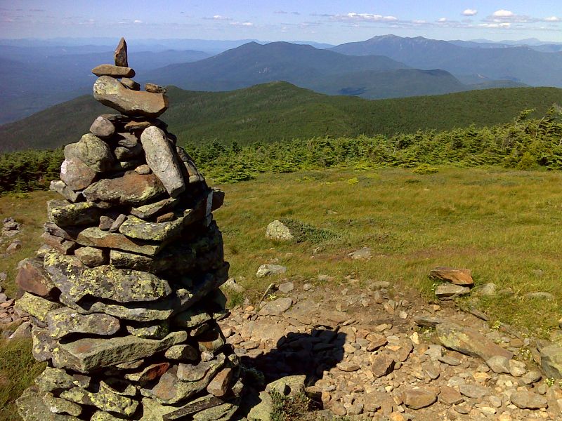 Cairn on the north side of Mt. Moosilauke, not far from summit.  Kinsman Ridge, Franconia Ridge and the Presidential Range are all visible.  Mt. Washington is the peak in the far distance on the far right side of the view.  GPS N44.0262  W71.8303  Courtesy pjwetzel@gmail.com