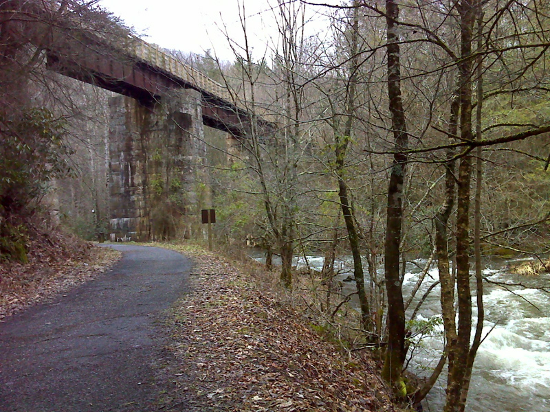 mm 3.4  The Luther Hassinger Memorial Bridge as seen from the access trail from the parking area on VA728.  The Appalachian Trail and the Virginia Creeper Trail use this bridge.  The access trail, also an old railroad bed,  meets the AT/ VA Creeper Trail at Creek Junction.  Note the raging rain swollen Whitetop Laurel Creek on the right.  Picture taken in February 2012.    Courtesy pjwetzel@gmail.com