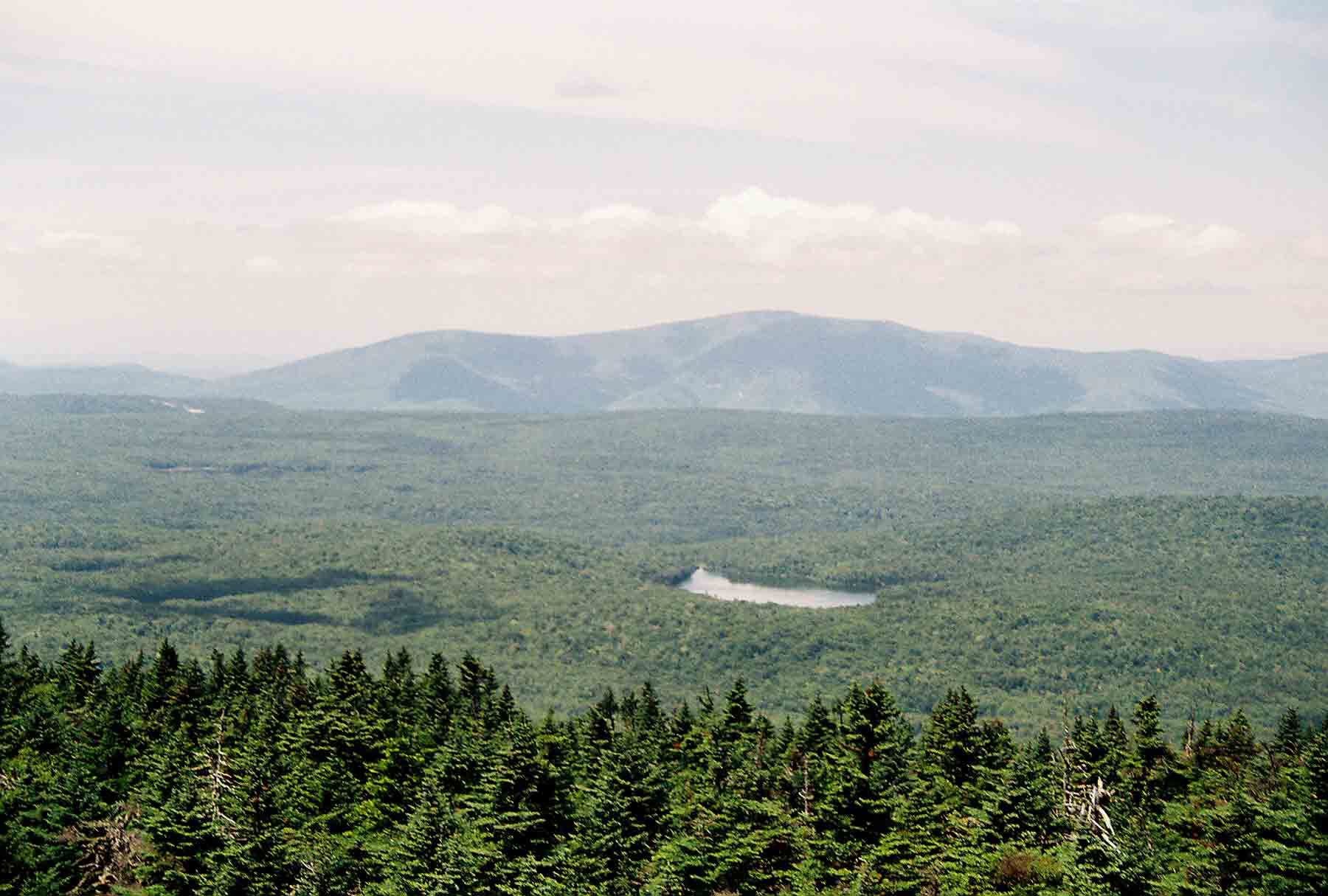 mm 13.7 - View to west from Stratton Firetower. Lake visible is Statton Pond. Though not visible there is a sharp dropoff at the far side of the plateau to the Valley of Vermont. The mountains visible are the Taconics on the west side of the valley. Courtesy dlcul@conncoll.edu