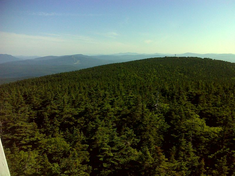 mm 13.7 View north from the Stratton Mountain firetower.  The north summit of Stratton Mt.  where the ski area is located is in the foreground.  Bromley Mountain and its ski area are in the distance.  GPS N43.0862 W72.9250  Courtesy pjwetzel@gmail.com